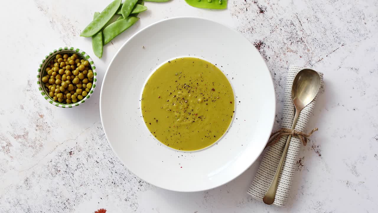 sopa cremosa con guisantes verdes en un plato blanco de cerámica