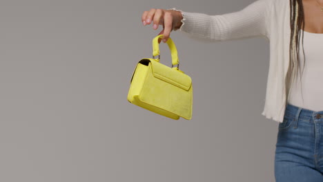 close up of female social media influencer producing user generated content holding out yellow fashion handbag 1