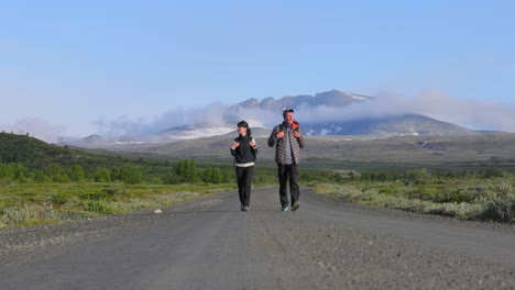 couple hiking with backpacks on a road with mountains in the background. dovrefjell sunndalsfjella national park is a national park in norway. beautiful nature norway natural landscape.