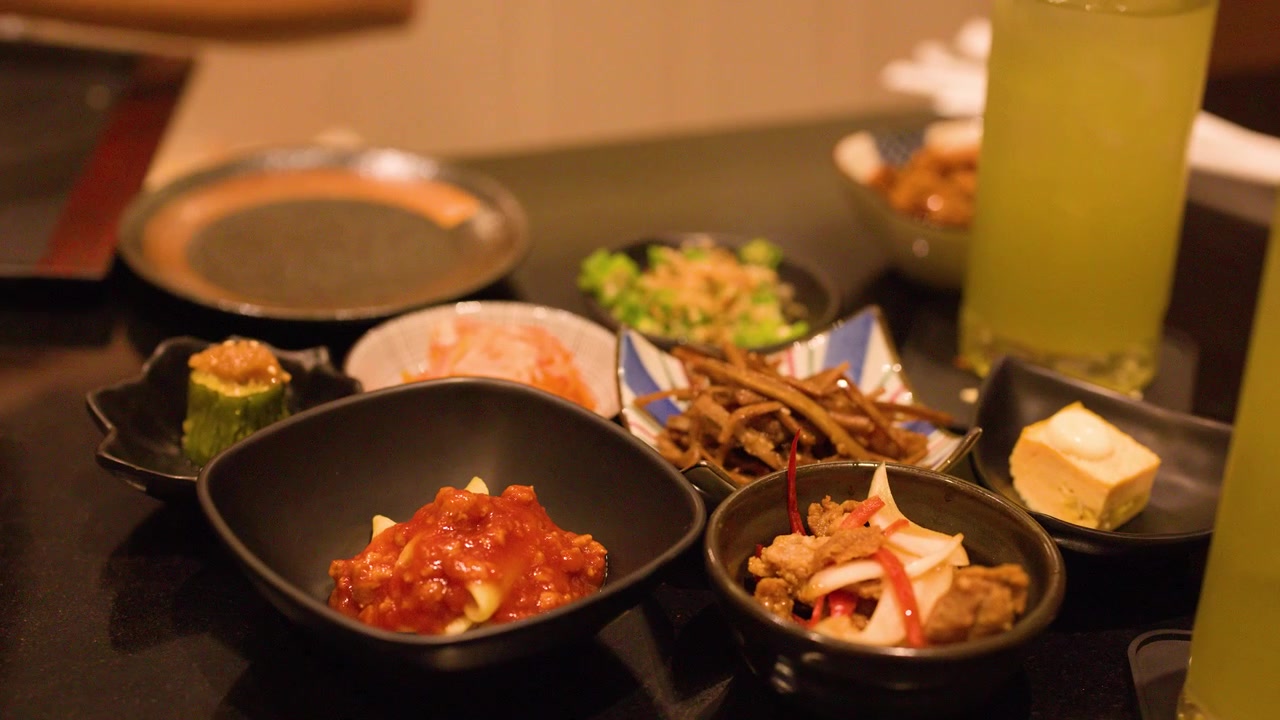 居酒屋で伝統的な日本料理の様々な小皿に手を伸ばす人