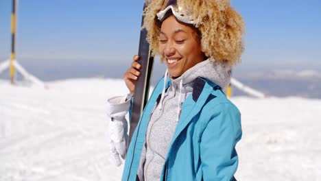 Thoughtful-young-woman-standing-holding-her-skis