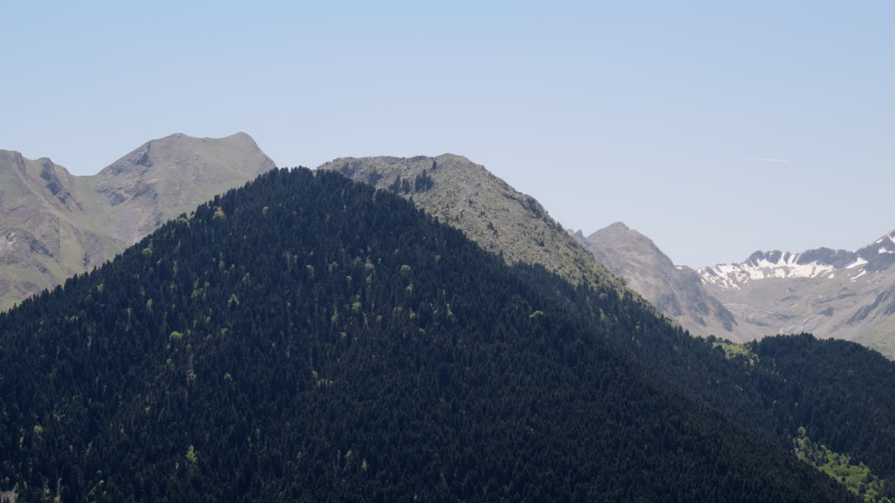 Pengambilan gambar geser ke kanan punggung gunung, puncak gunung yang tertutup salju musim semi pada Hari yang Cerah.