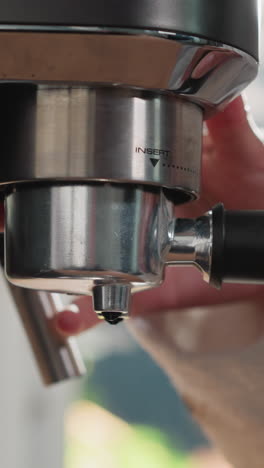 una mujer instala un portafiltro en una máquina de café de primer plano. una mujer ensambla una cafetera para preparar una bebida negra caliente en casa. un aparato de bebida con cafeína