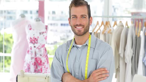 guapo diseñador de moda sonriendo a la cámara con los brazos cruzados