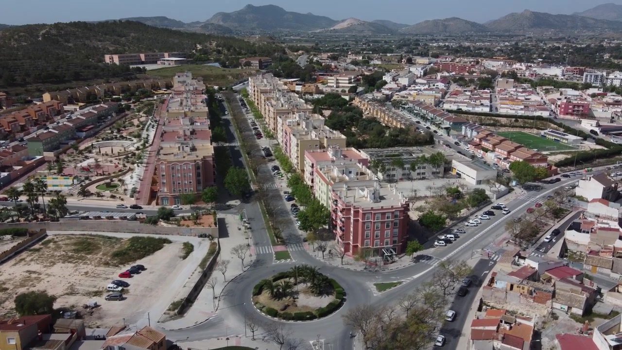 Vista aérea sobrevoando empreendimentos habitacionais modernos e novos bairros residenciais em Aspe, Alicante, Espanha. Conceito de expansão urbana, crescimento imobiliário e arquitetura mediterrânea ensolarada