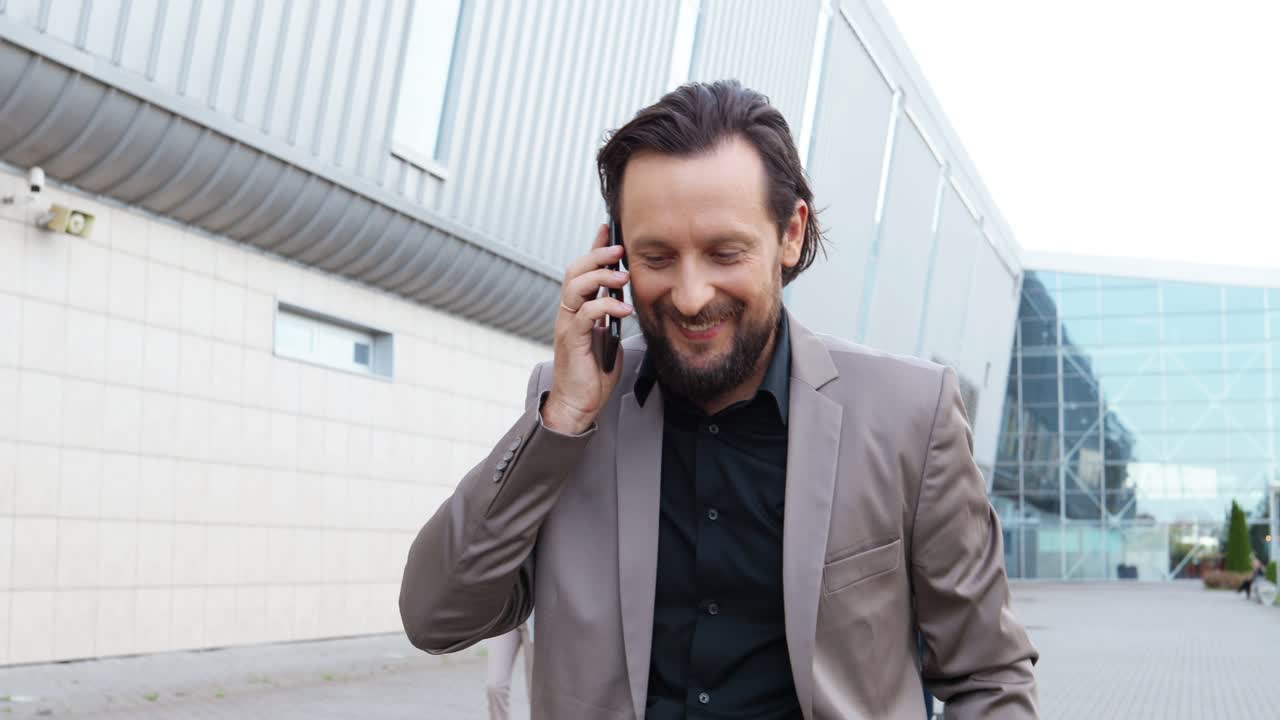 세련된 옷을 입고 길을 걷고 스마트폰으로 이야기하는 백인 사업가