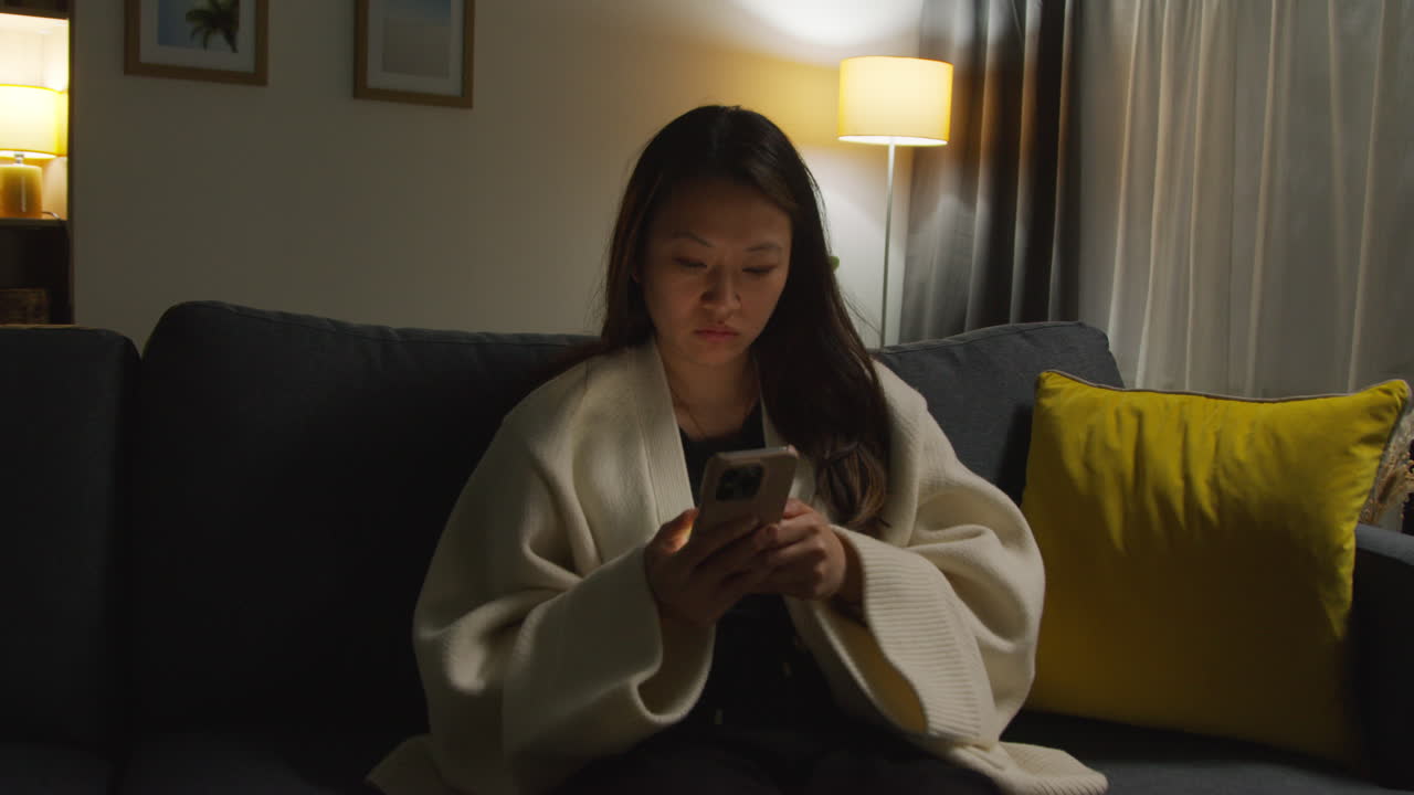 женщина проводит вечер дома, лежа на диване с мобильным телефоном, просматривая интернет или социальные сети 14