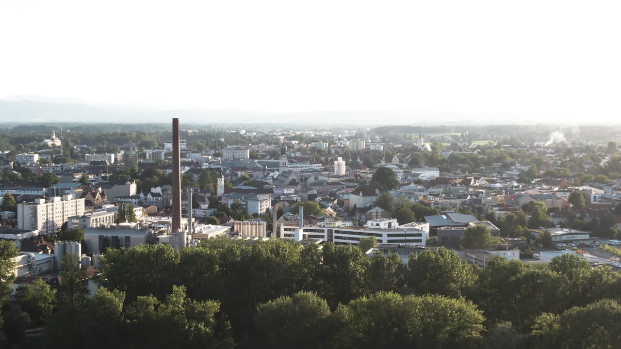 Closer Aerial Shot in the sunset of the city of Rosenheimwith industry and the city centre. In the distance aremountains and a lot of green trees.