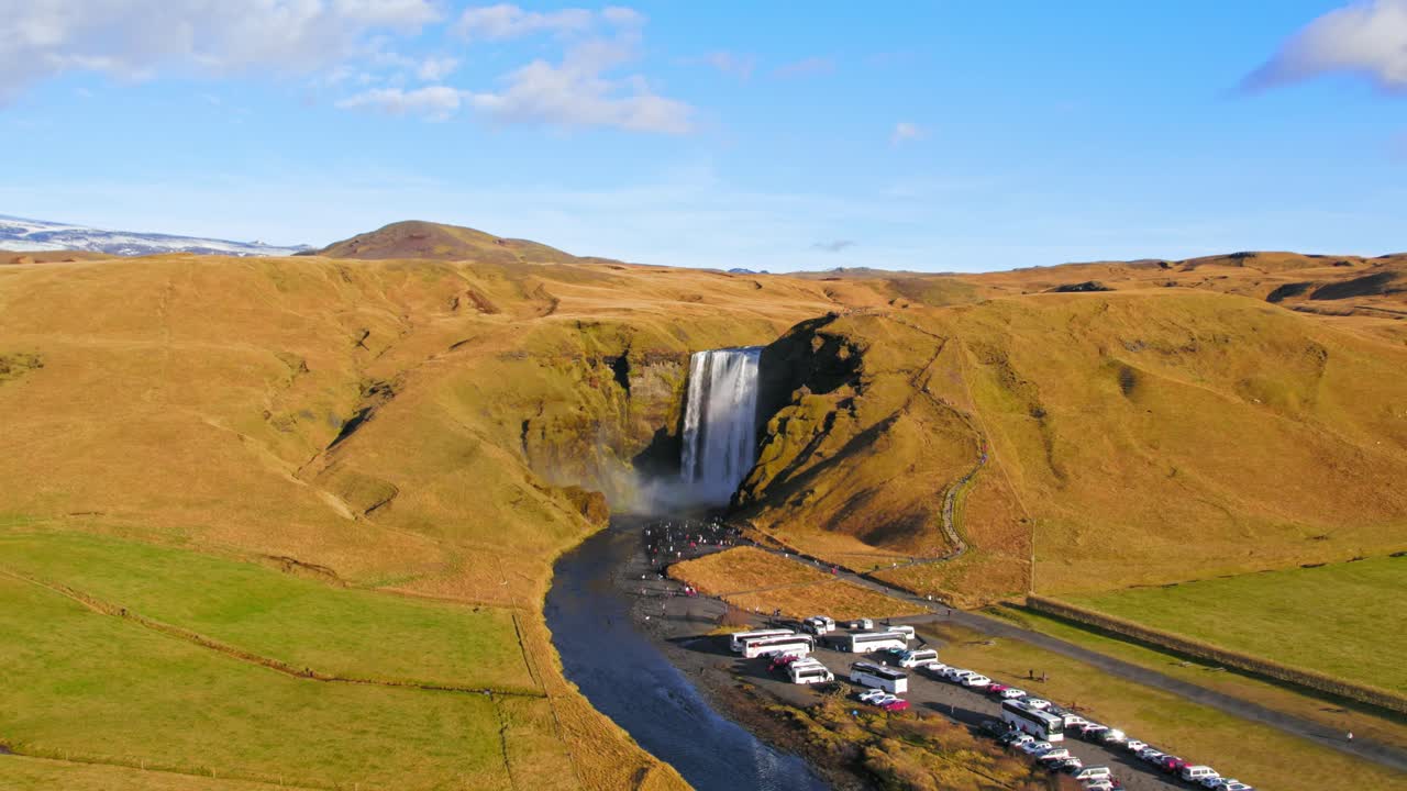 imágenes aéreas de drones del icónico destino turístico de skogafoss en islandia con autos estacionados y autobuses cerca de la cascada