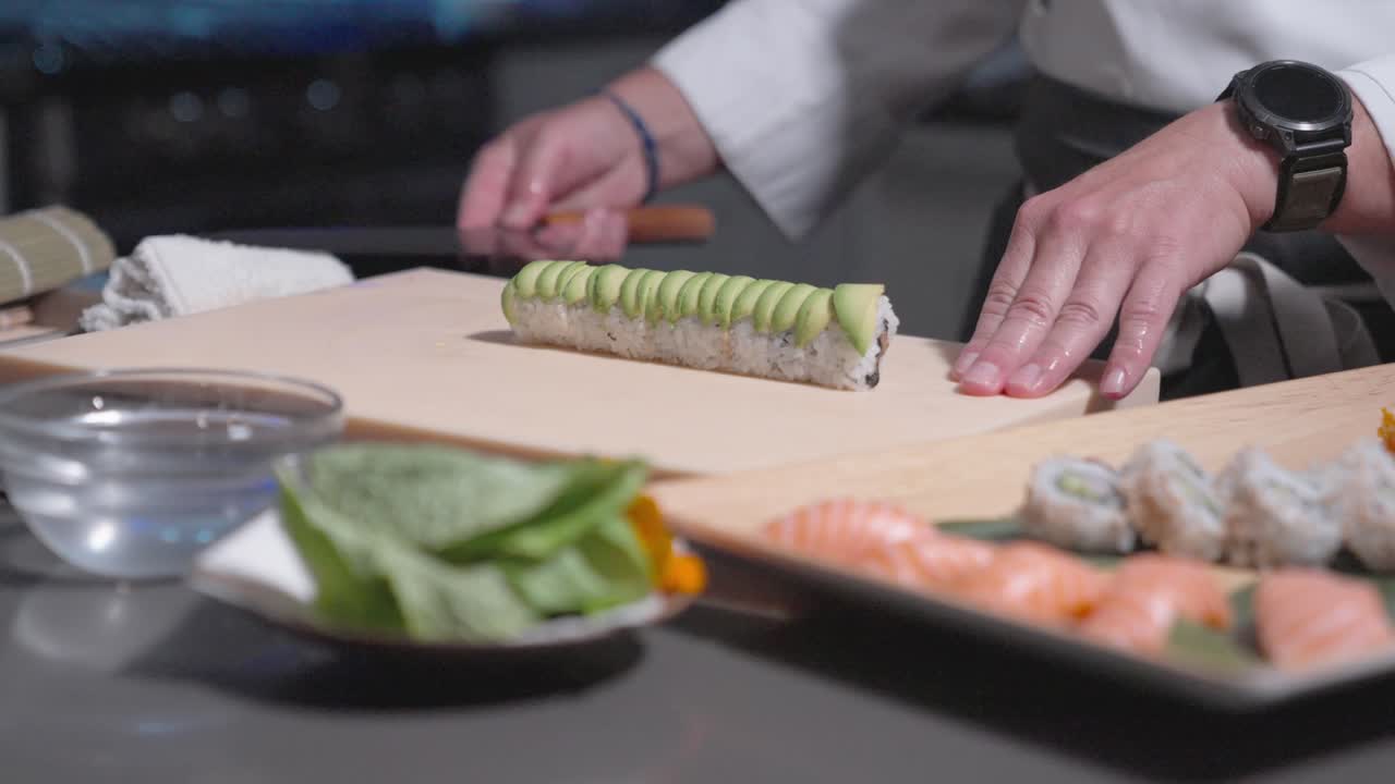 A sliding shot captures sushi chefs carefully placing avocado sushi rolls into a decorative bowl, showcasing precision and presentation. Perfect for culinary, sushi, and food styling content.