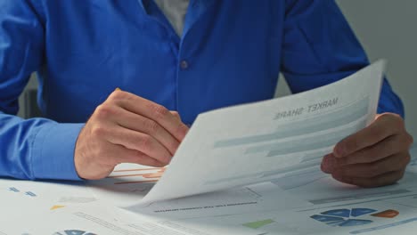 close-up businessman takes notes in documents, graphs and works behind a laptop