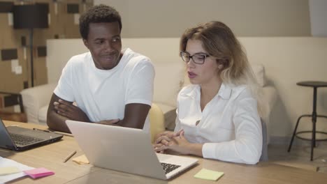 diverse couple of colleagues sitting at table with laptops