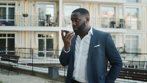 Afro-businessman-talking-mobile-phone-outside.-African-man-standing-near-office