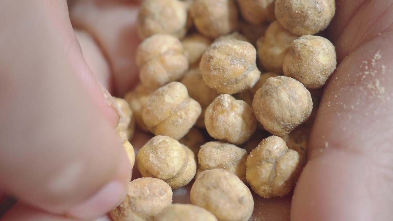 Primo piano di una mano che prende uno snack di ceci tostati