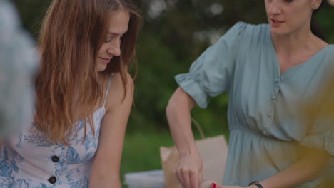 a group of young women in nature in the park hold a master class in clay modeling. the female explains to the group how to correctly sculpt the product. communication a common hobby women's circle