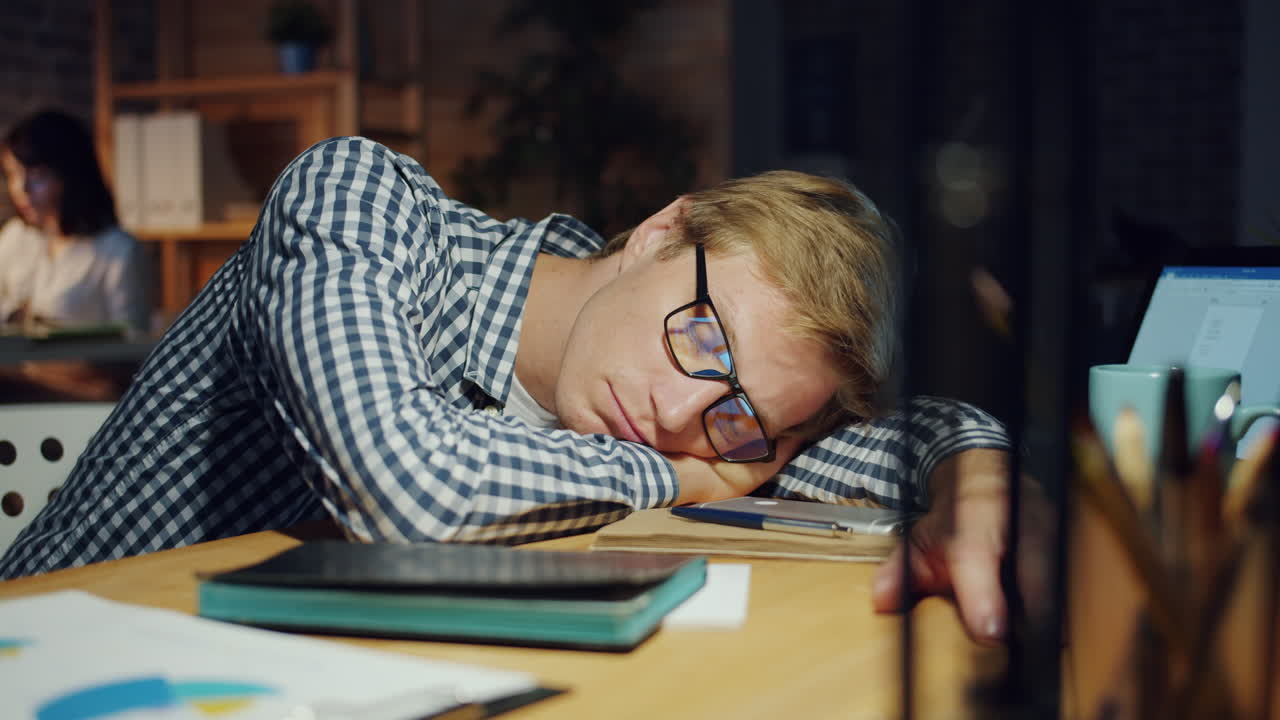 Dipendente stanco che dorme alla sua scrivania di notte