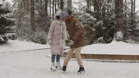 couple ice skating in snowy park