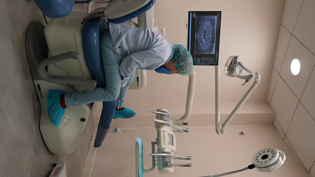 Complaining elderly patient in a dental chair checking oral treatment to follow on a paper with instructions. Vertical
