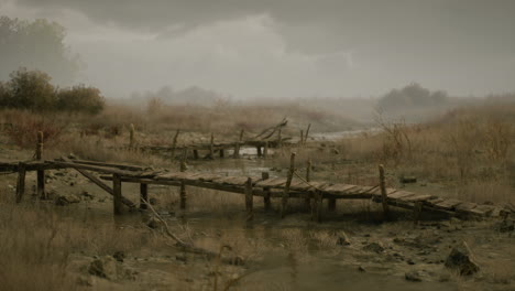 weathered wooden bridge over muddy terrain during a gloomy day