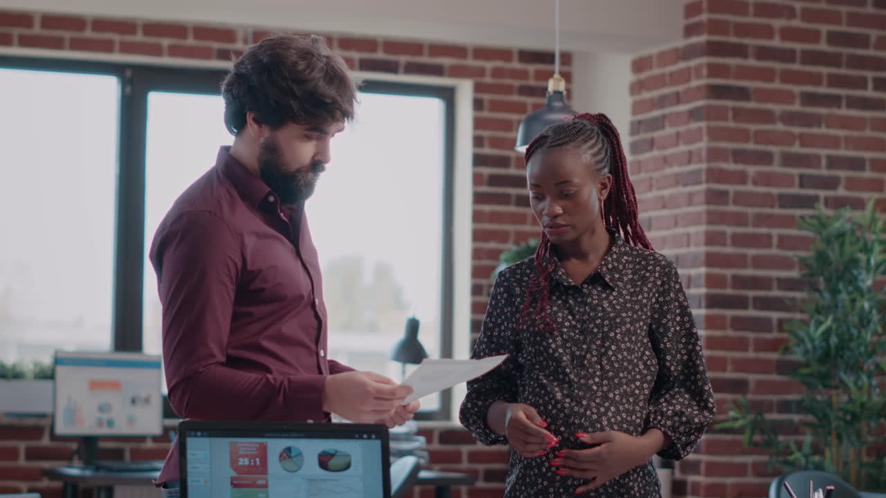 Pregnant adult and colleague giving highfive after finishing business project