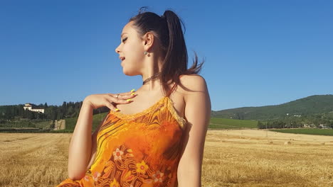 young brunette girl singing towards camera in a wheat field at the beginning of summer