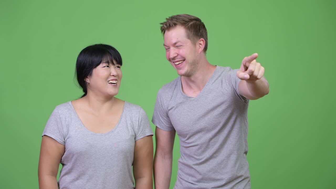 Young multi-ethnic couple pointing finger together