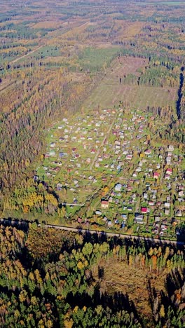 small village nestled in autumn forest – latvia seen from helicopter window