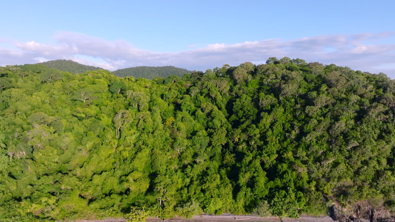 Drone shot reveal over a forested tropical islands to reveal a tropical coastline in the Whitsunday Islands, QLD, Australia