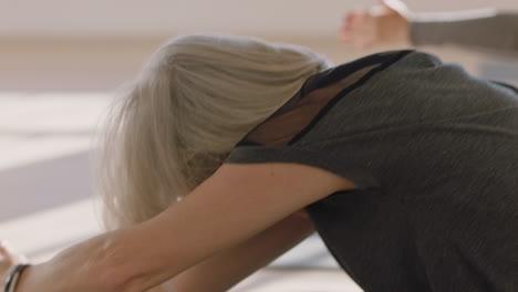 yoga class beautiful old woman exercising healthy meditation practice head to knee forward bend pose enjoying group physical fitness workout in studio