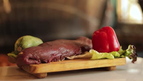 carne cruda de res colocada en una bandeja de madera con calabazas frescas y pimienta roja