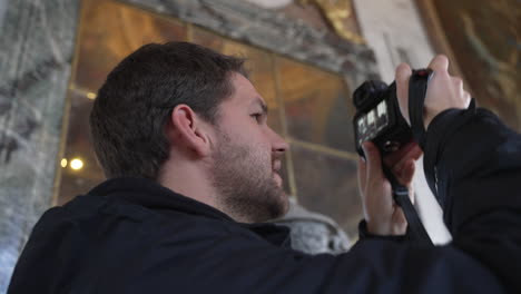 close-up of a man taking pictures inside the palace of versailles, france