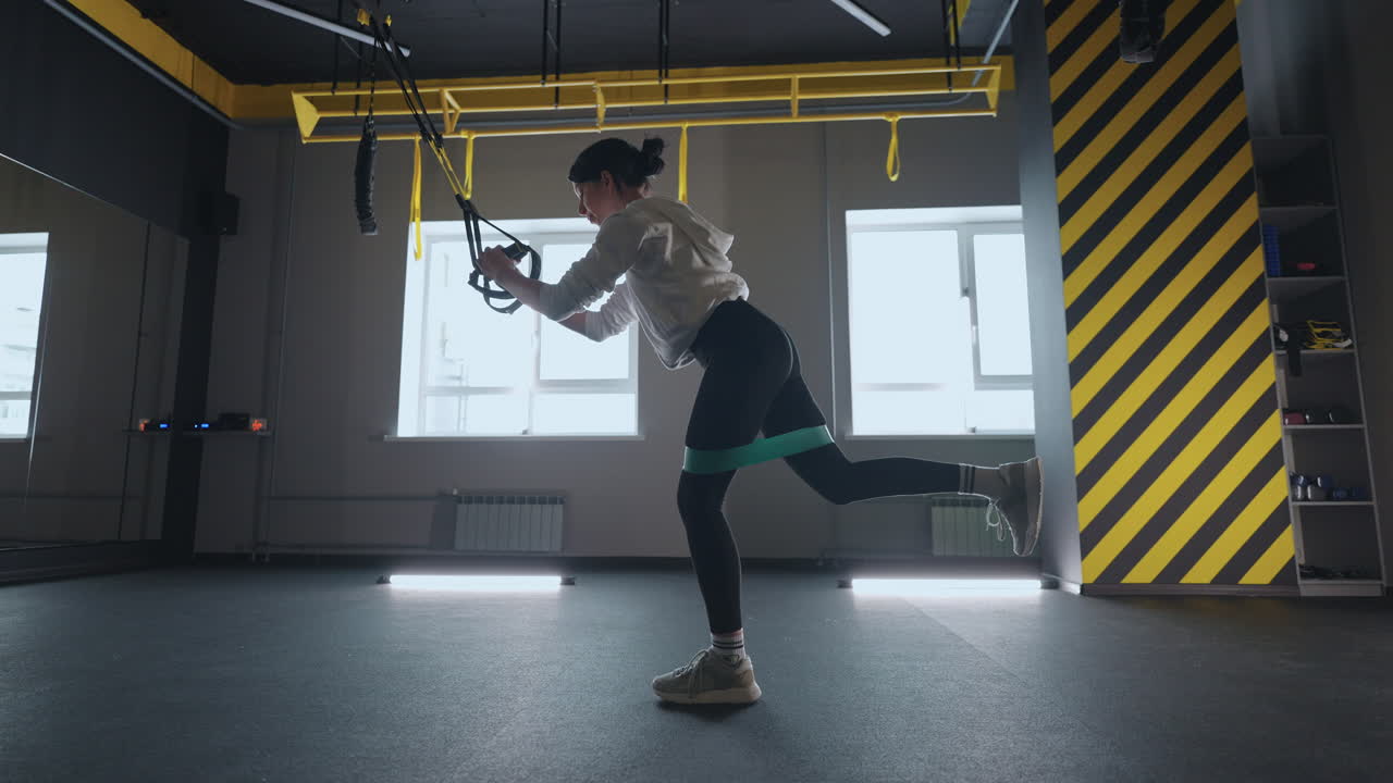 fitness TRX training exercises at gym woman push-up workout. Attractive woman doing exercise for hands in gym. core abs crossfit oblique training with fitness straps in the gym's studio. TRX