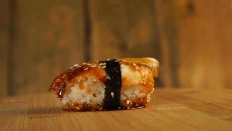 sushi with fish, rice and seaweed rotate on a wooden turntable.