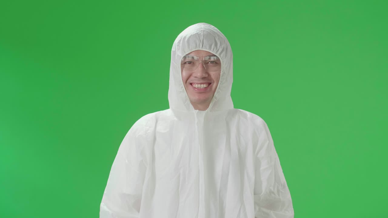Asian Male Wearing Personal Protective Equipment Uniform Ppe And Smiling To Camera In Green Screen Studio