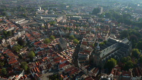 flying towards the prominent landmark and structure of sint-jan church, old town hall and market stands in in gouda metropolitan, netherlands