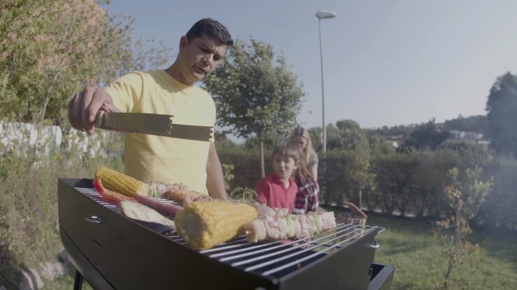 Man cooking meat and vegetables on barbecue grill outdoors