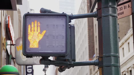 pedestrian walk signal turning from orange hand stop to walk in daytime new york city. slow motion.