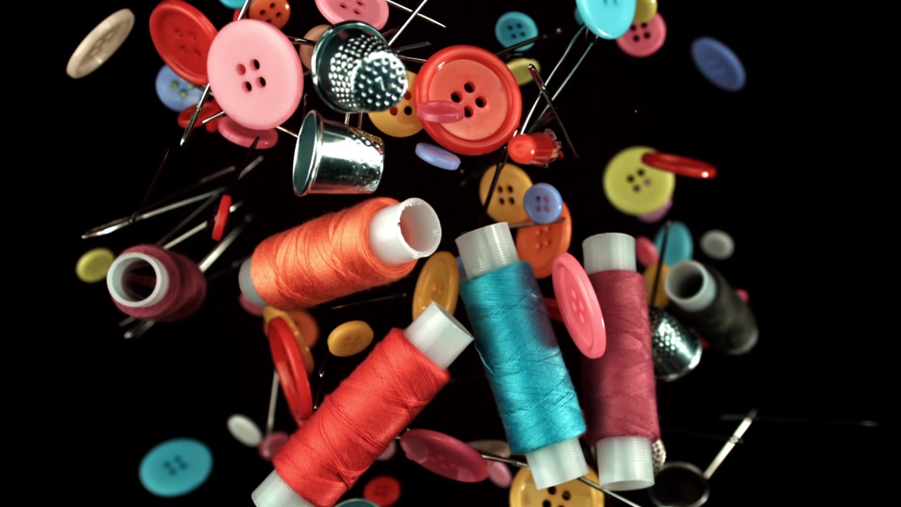 Colorful Sewing Supplies Falling in Slow Motion on Black Background