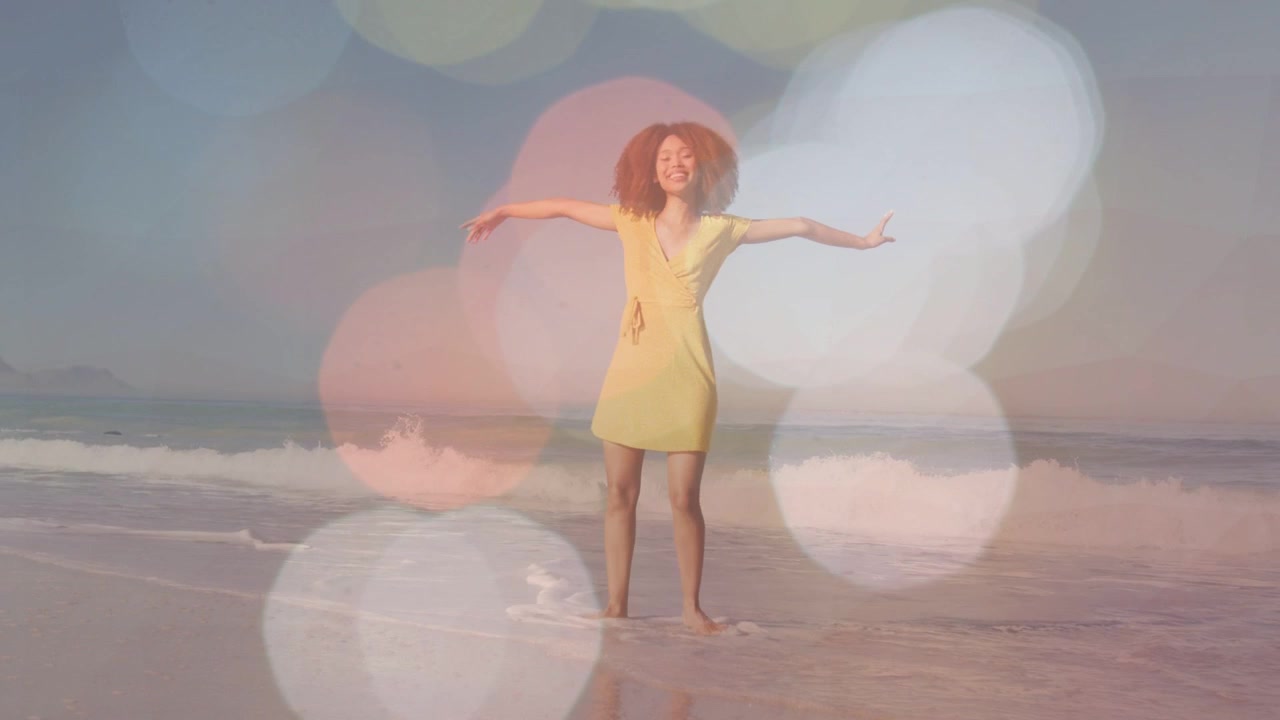 Woman wearing yellow dress wading and spinning on shoreline, adding bokeh overlays for fashion ad