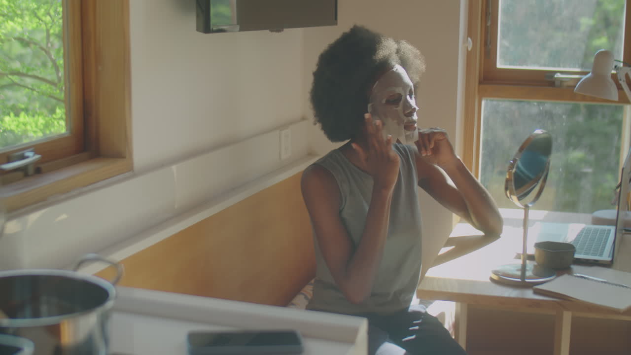 Black Woman Applying Sheet Mask to Face at Home