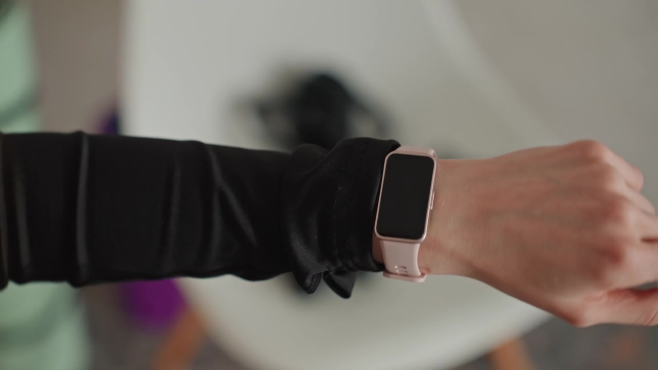 Kvinde forbereder sig på yoga. Kvinde justerer smartwatch under træning. Blide bevægelser, mens kvinden gør yogaudstyret klar. Rolig atmosfære, mens kvinden indstiller sit smartwatch til en mindful yogasession derhjemme.