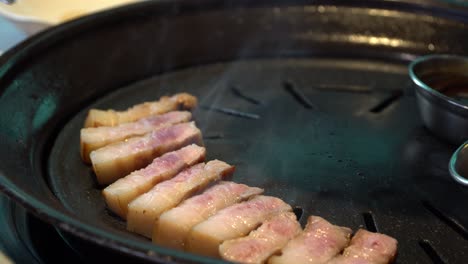 smoke coming out from charcoal griller with korean pork belly - samgyeopsal in korean restaurant