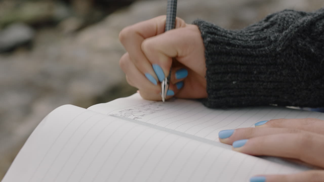 close up hands woman writing in diary journal teenage girl expressing lonely thoughts on seaside beach
