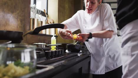 caucasian female chef teaching diverse group preparing dishes and smiling