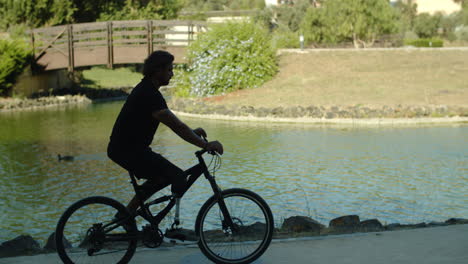 Handheld-shot-of-serious-man-with-disability-riding-bike-in-park