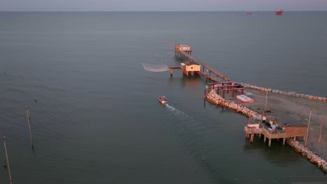 Luftaufnahme-Von-Fischerhütten-Am-Ufer-Der-Mündung-Bei-Sonnenuntergang,-Italienische-Fischermaschine,-Genannt-&quot;Trabucco&quot;,-Lido-Di-Dante,-Ravenna-In-Der-Nähe-Des-Comacchio-Tals