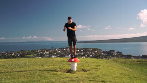 Young-caucasian-tourist-standing-on-metal-mushroom-sculpture-vent-on-Mount-Victoria,-Auckland,-New-Zealand