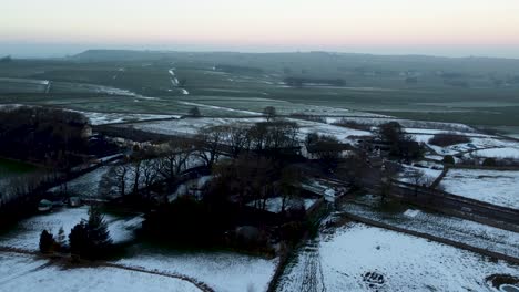 Verschneite-Landschaft,-Auf-Der-Straße-Fahrende-Autos-Und-Am-Leuchtend-Farbigen-Horizont-Zeichnen-Sich-Grüne-Wiesen-Ab