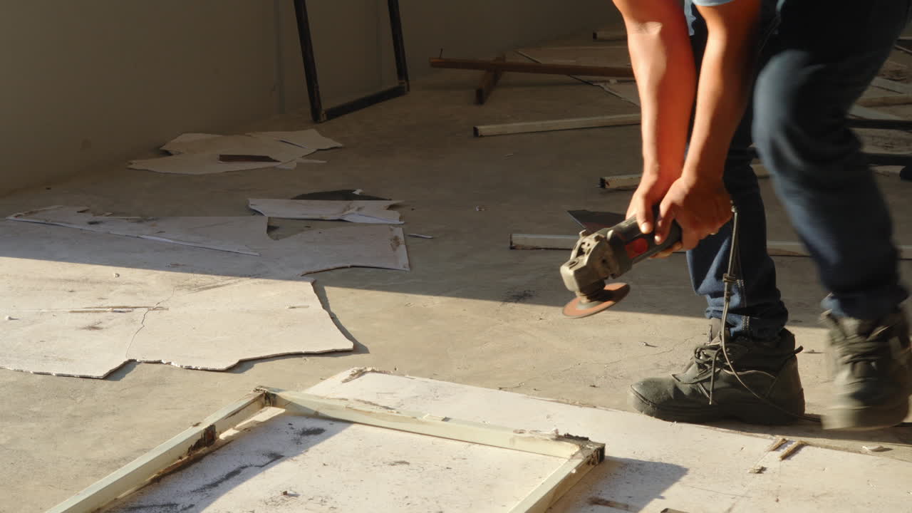 Male Worker Removing Welding On The Corner Of A Metal Frame With A Grinder. tilt-up