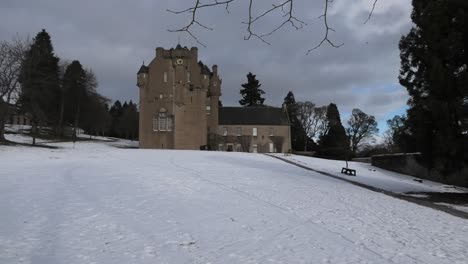 crathes castle in snow sunlit with overcast sky
